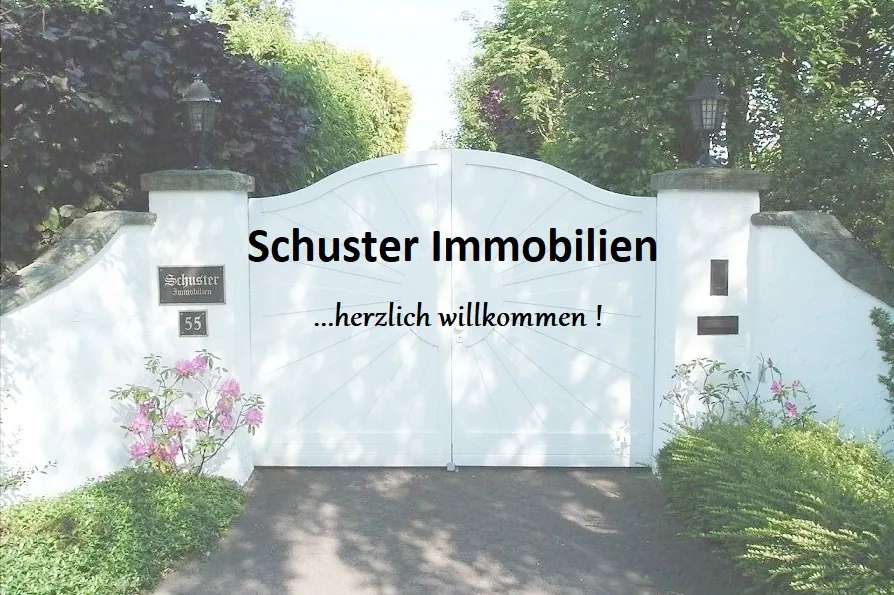 Einfahrtstor mit dem Schriftzug „Schuster Immobilien – herzlich willkommen!“